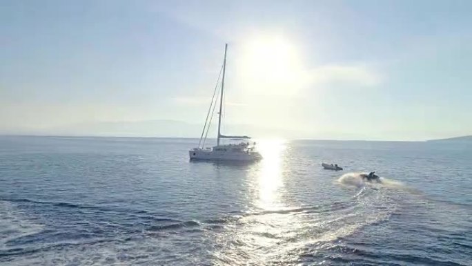 附近白色帆船双体船游艇和喷气滑雪的鸟瞰图。美丽的天气，平静的镜子像大海，阳光明媚。