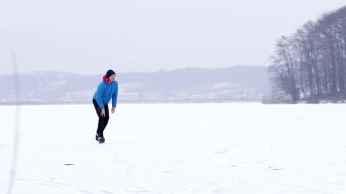 4k十几岁的男孩滑冰，在冰冻的湖上跑步，慢动作
