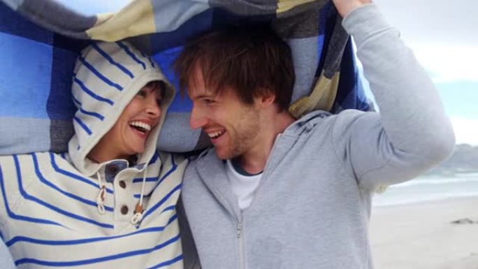 幸福的夫妇躲在海滩的毯子里