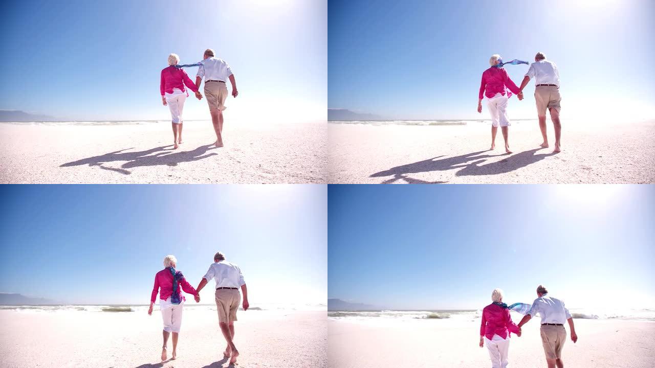 一对老年退休夫妇一起沿着海滩散步的后视图
