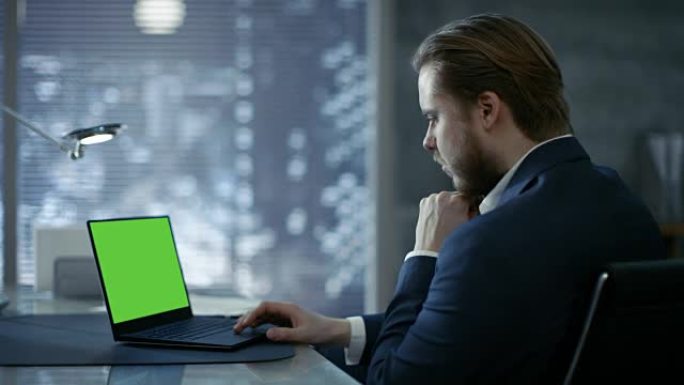 年轻而有远见的商人坐在他的桌子旁，在带有绿色模拟屏幕的笔记本电脑上打字。她的办公室看起来很现代，带有