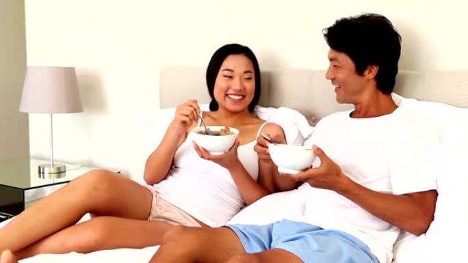 夫妇在床上吃一碗麦片