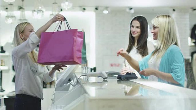 两个快乐的年轻女孩正在百货公司的收银台买衣服。