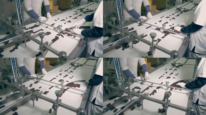 巧克力糖果的俯视图由工人分类并沿着传送带进一步移动