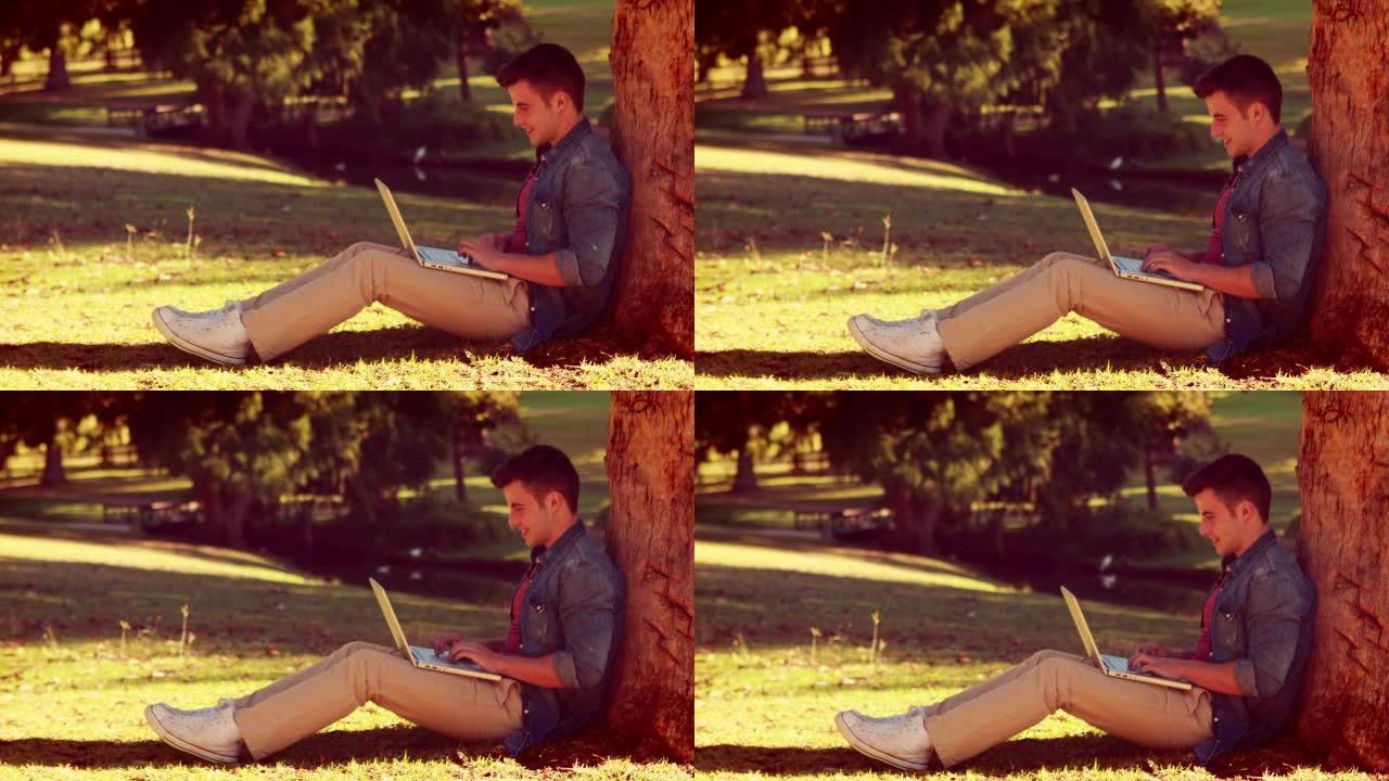 年轻人坐在树上，用他的笔记本电脑