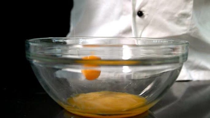 厨师将生鸡蛋添加到玻璃碗中