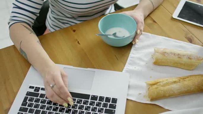 吃早餐时在笔记本电脑上工作的女人