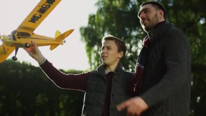 父子俩在公园里检查飞机模型并计划发射。