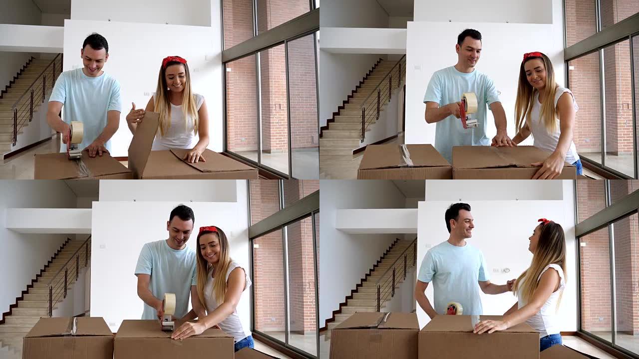 幸福的年轻夫妇用胶带关闭箱子，他们要搬到新家
