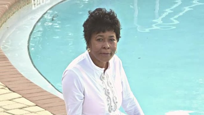 坐在游泳池边的成熟非裔美国妇女