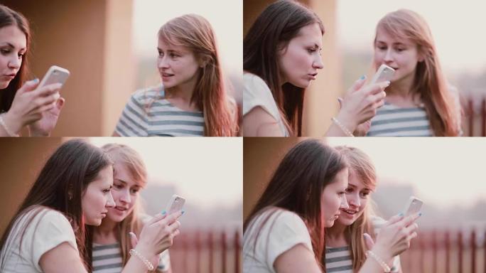 两个漂亮的女人正在使用智能手机并进行对话。朋友在夏天的户外手机上观看照片