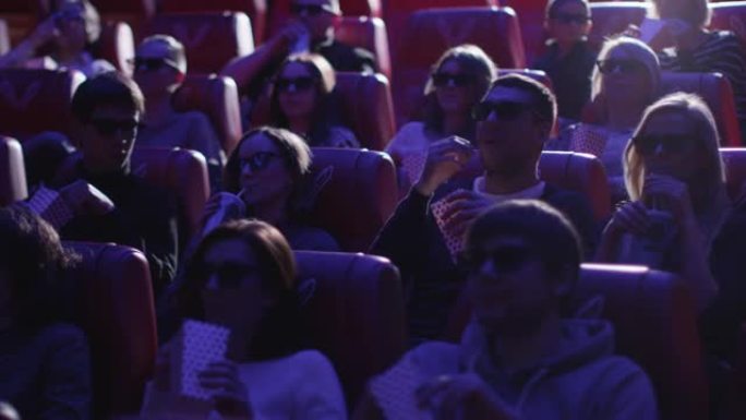 一群戴着3d眼镜的人正在电影院观看电影放映。