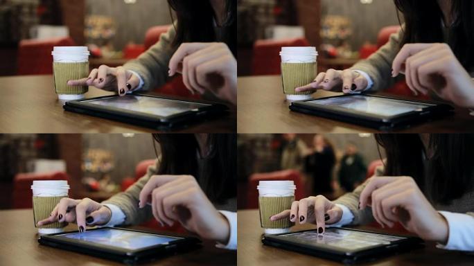 在咖啡馆使用平板电脑触摸屏的女人手