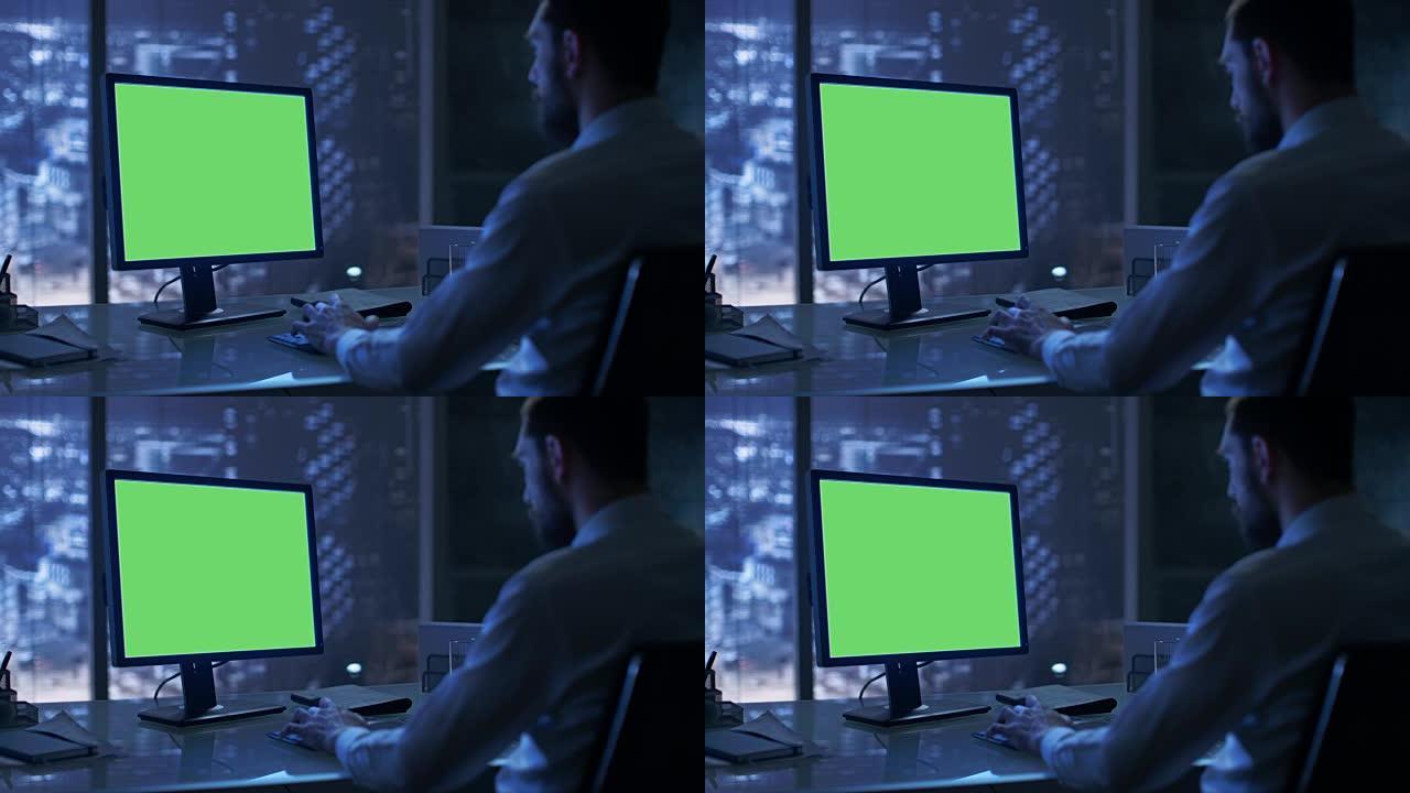 深夜，一个商人在他的私人办公室里用一台带有绿色模拟屏幕的个人电脑工作，可以看到大城市的窗户。