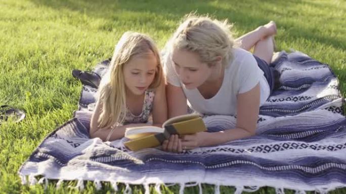 母女俩在外面的毯子上看书