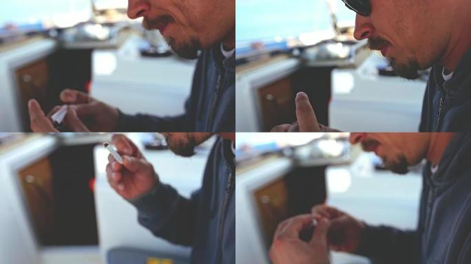 4k男子在帆船上滚动烟草香烟，实时