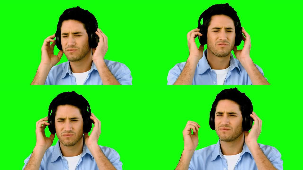男人在绿色屏幕上戴着耳机听音乐
