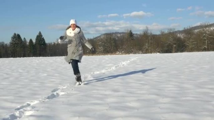 空中: 年轻女子在阳光明媚的日子里在雪中奔跑