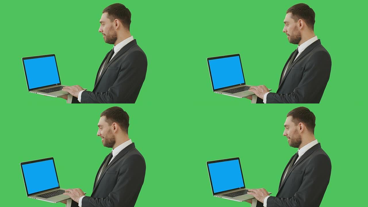 一个英俊的商人拿着笔记本电脑和触摸板的中等镜头。我们看到笔记本的蓝屏，都是在绿屏背景上拍摄的。