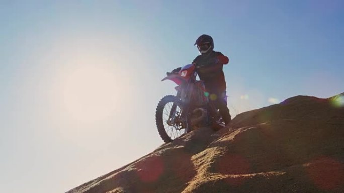 低角度镜头的专业摩托车越野赛摩托车骑手开车离开沙丘和下的地形。