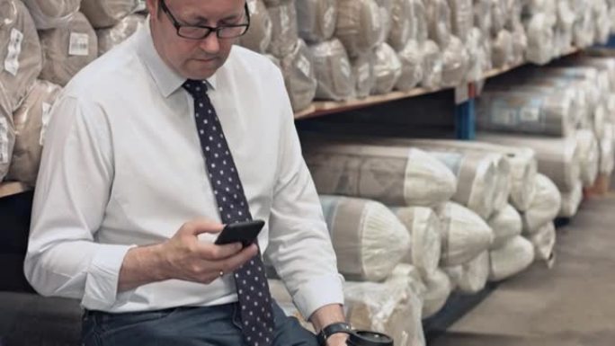 地毯工厂的经理在咖啡休息时使用智能手机