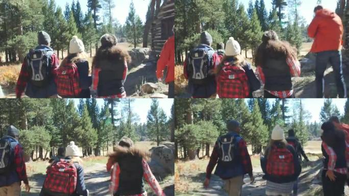 兴奋的朋友徒步穿越森林中的小屋，后视图，在R3D上拍摄