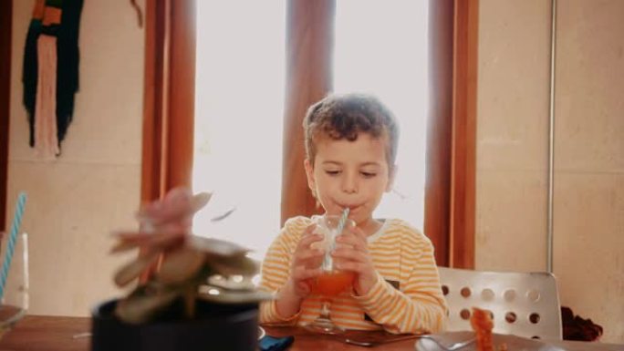小男孩在吃完早餐前喝新鲜橙汁