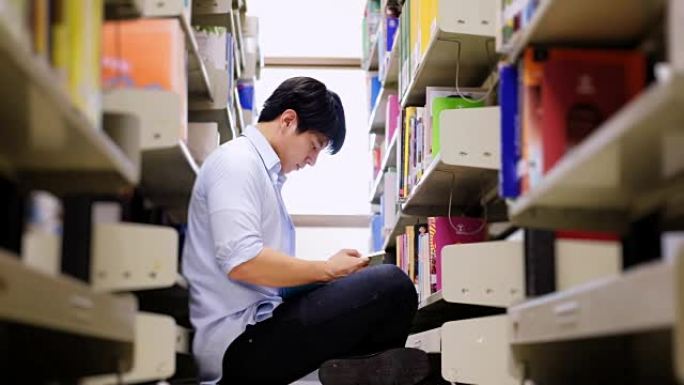 亚洲男大学生在图书馆阅读地板上进行学习研究。