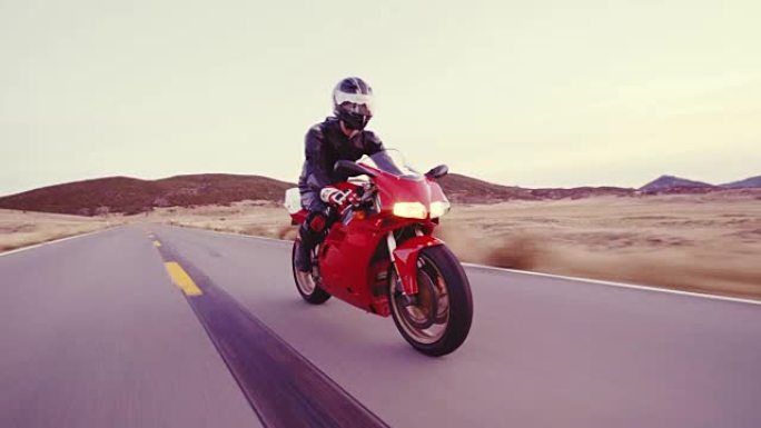 摩托车手骑着摩托车沿着直行的乡间小路在日落时高速行驶