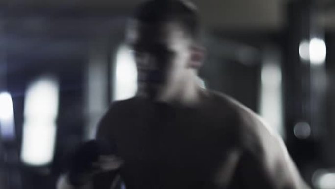 职业男拳击手正在黑暗的健身房训练拳打脚踢。