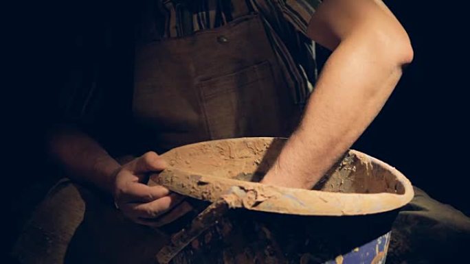 男性陶艺家的手在装有粘土的桶内缓慢移动。