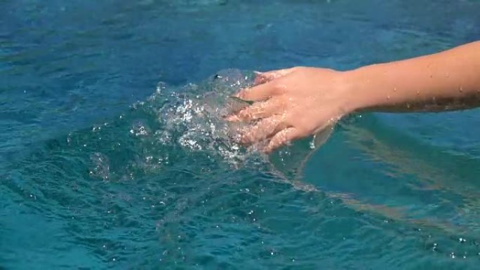 慢动作: 晒黑的女孩在水面上滑动手的细节
