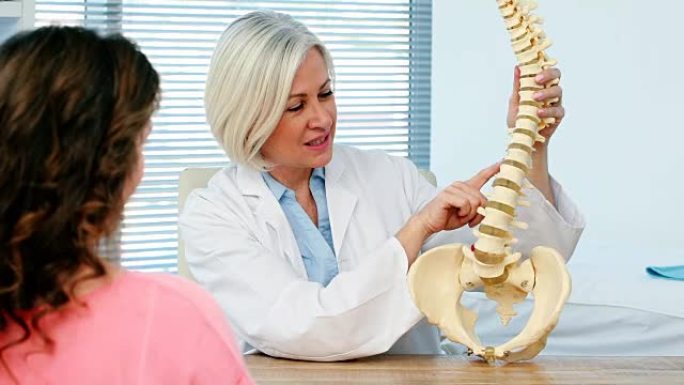 女医生向女性患者解释脊柱模型
