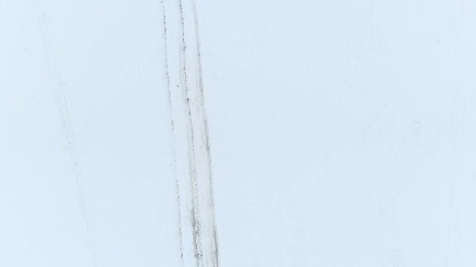 空中4K: 汽车轨道蜿蜒穿过积雪覆盖的田野