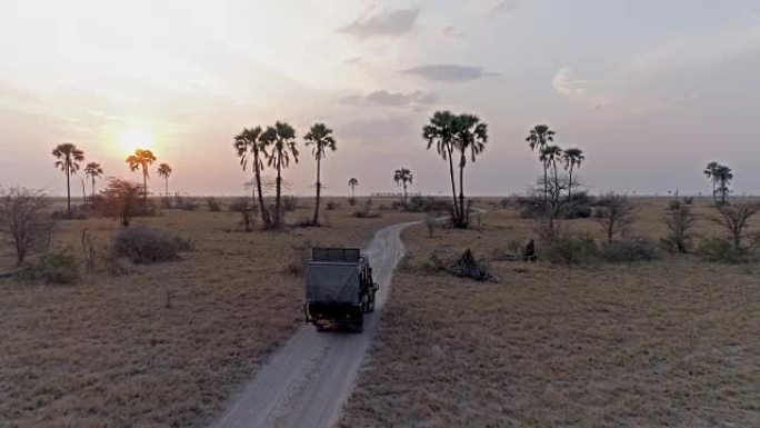博茨瓦纳，一辆4x4野生动物园车辆驾驶穿过Makgadikgadi平底锅的鸟瞰图，背景是日落