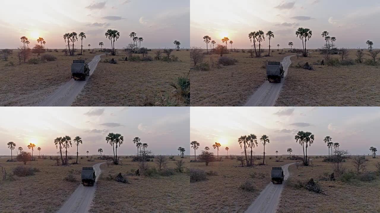 博茨瓦纳，一辆4x4野生动物园车辆驾驶穿过Makgadikgadi平底锅的鸟瞰图，背景是日落