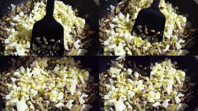 准备食物，蘑菇和洋葱在平底锅中油炸，慢动作搅拌，加入煮鸡蛋