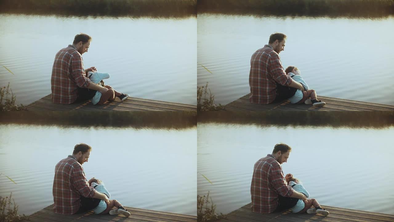 白人男子和小男孩坐在湖码头上。父子在一起。幸福的关系。抚养孩子。4K