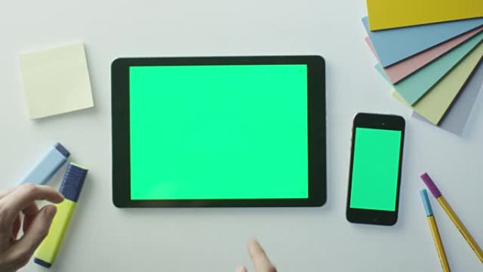 设计师正在使用带有绿屏的平板电脑和手机。非常适合使用模型。在红色电影摄影机上拍摄