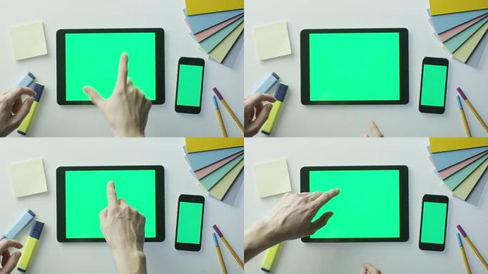 设计师正在使用带有绿屏的平板电脑和手机。非常适合使用模型。在红色电影摄影机上拍摄