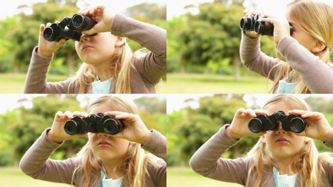 可爱的小女孩在公园里用双筒望远镜
