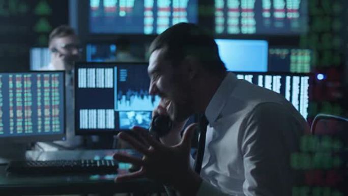 在一间满是显示屏的黑暗办公室里，股票经纪人一边忙着打电话，一边在电脑上工作。