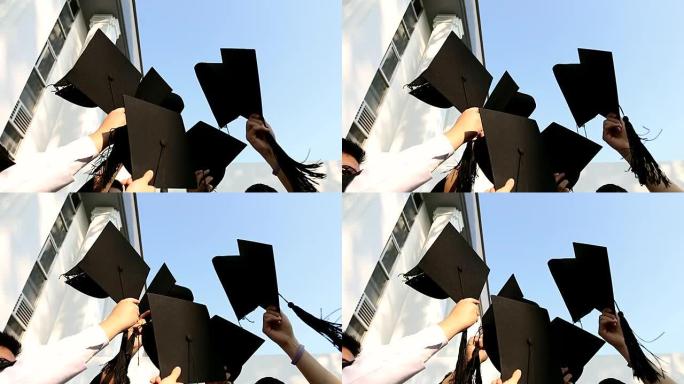 穿着长袍的快乐学生在空中展示砂浆板。教育，毕业和人们的观念。