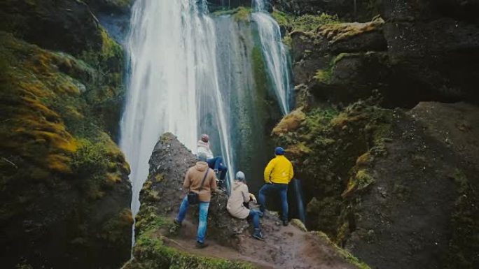 一群游客在山顶上休息，并在冰岛的gljufragui瀑布上眺望的鸟瞰图