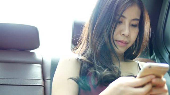 出租车上的年轻女子在智能手机上上网