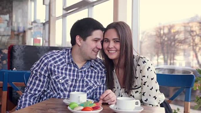 幸福的情侣在咖啡馆笑着喝茶。用平板电脑取乐。第一次约会