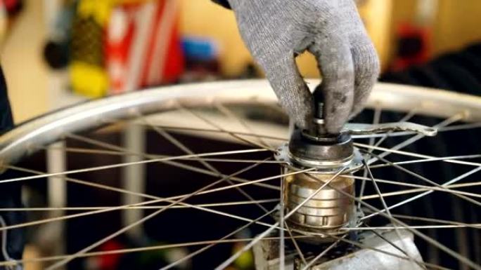 自行车车轮防护手套装配机构中男性手的特写镜头拧紧金属螺钉。工作、人和职业概念。
