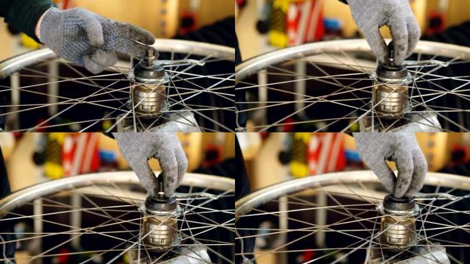 自行车车轮防护手套装配机构中男性手的特写镜头拧紧金属螺钉。工作、人和职业概念。