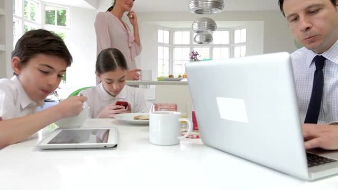 在早餐桌上使用数字设备的家庭