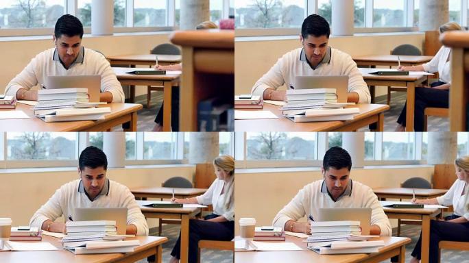 年轻的印度男大学生在校图书馆使用笔记本电脑